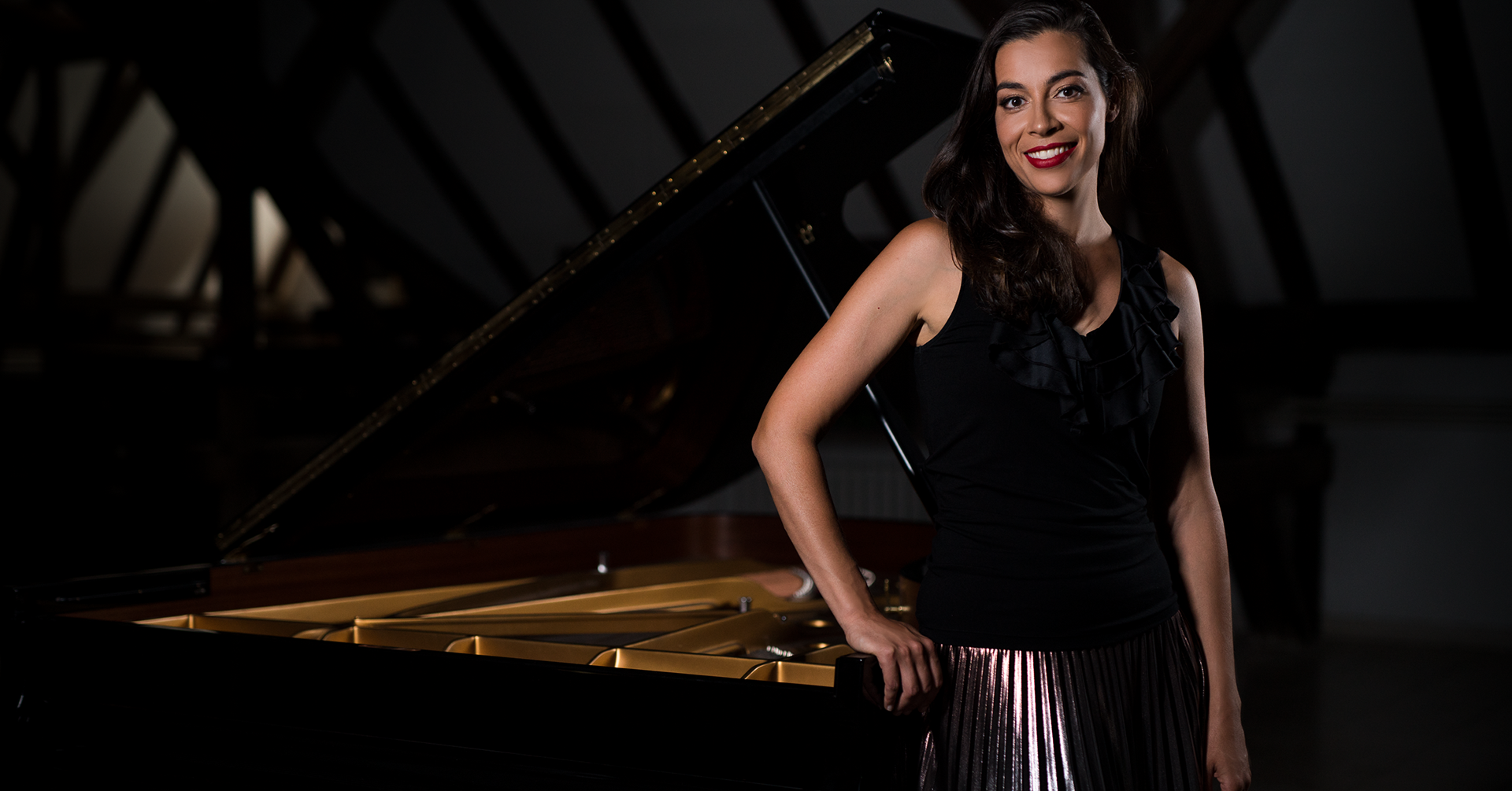 An image of Sibila Konstantinova standing next to a piano.