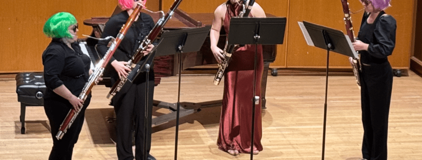 A photo of four students in the playing bassoons on stage.