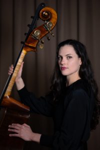 A photo of Kathryn Schulmeister holding a double bass.