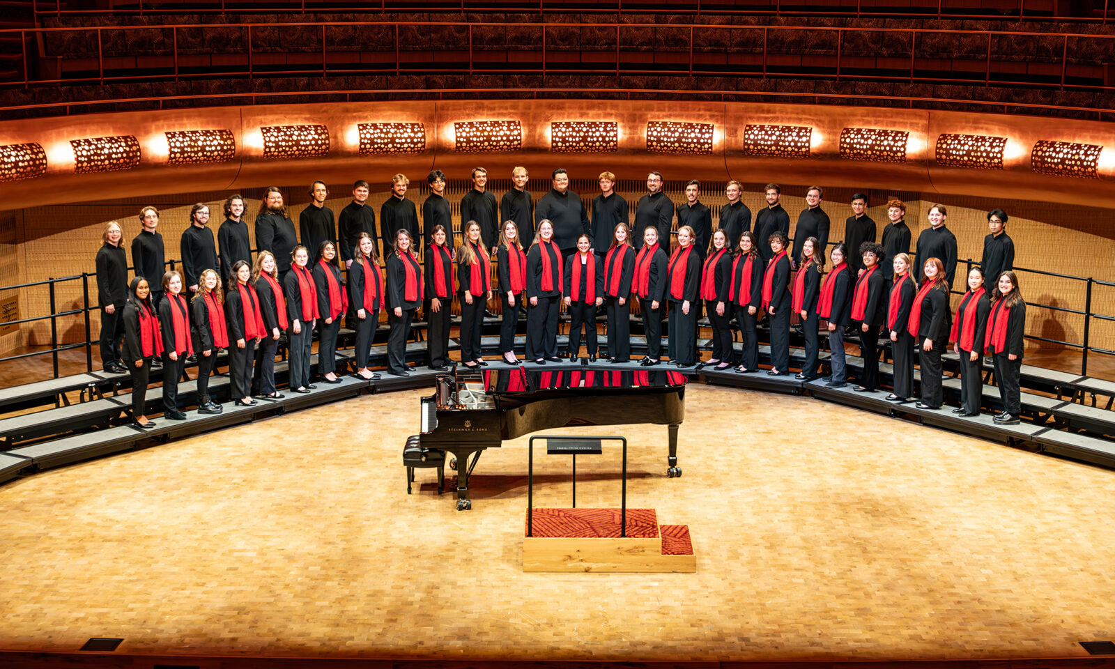 A photo of the UW Concert Choir posing as a group on stage at the Hamel Music Center.