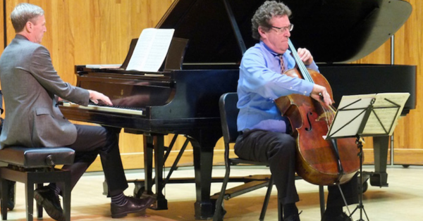 A photo of Parry Karp playing cello on stage with a pianist.