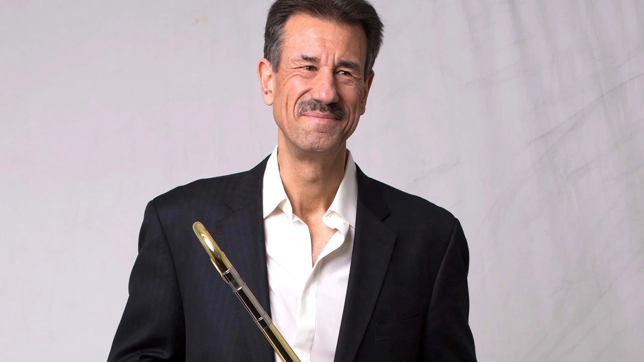 A photo of John Fedchock holding a trombone.